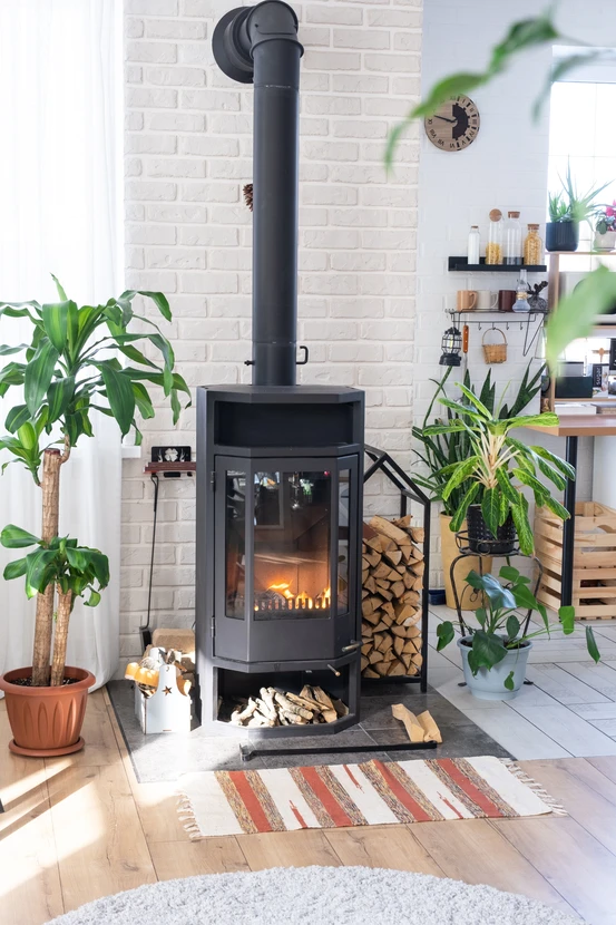 Intérieur moderne avec poêle à bois noir en fonte, cheminée tubulaire droite, mur de briques blanches