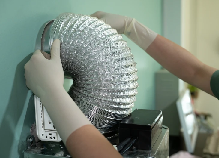 Intérieur de salle de bain carrelée blanche, homme effectuant l'installation d'une grille d'aération murale